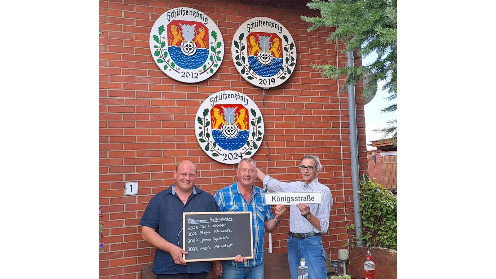 Tim Wischhöfer (v.l.), Heinz Wischhöfer und der aktuelle Schützenkönig Karl-Heinz Hellmann vor dem Haus Im Winkel 1, an dem jetzt drei Königsscheiben hängen.  (Foto: gi)