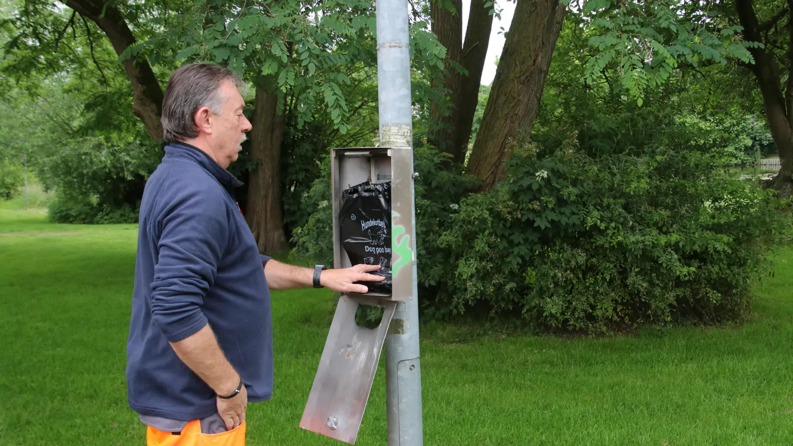 Jörg Behnecke füllt einen Hundekotbeutelspender am tollen Teich auf.  (Foto: gi)