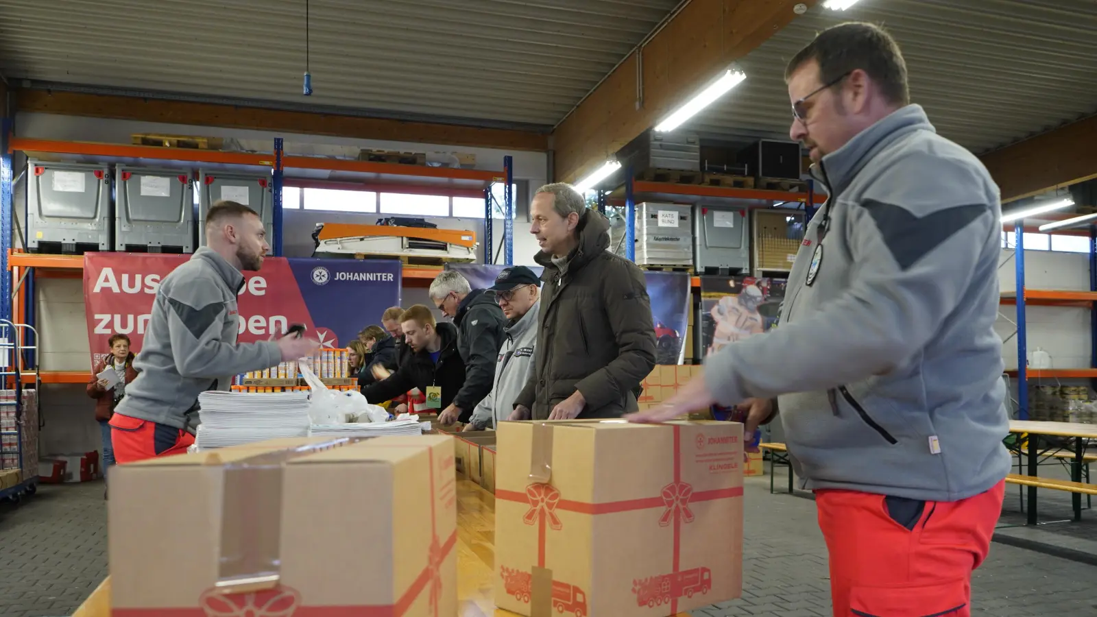 In der Fahrzeughalle: Helfer packen Pakete. (Foto: JUH/Heun)