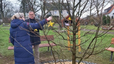 Die ersten Erinnerungssterne werden von Pastorin Anja Sievers und Samtgemeindedirektor Mike Schmidt an den den Taschentuchbaum gehängt. (Foto: gk)