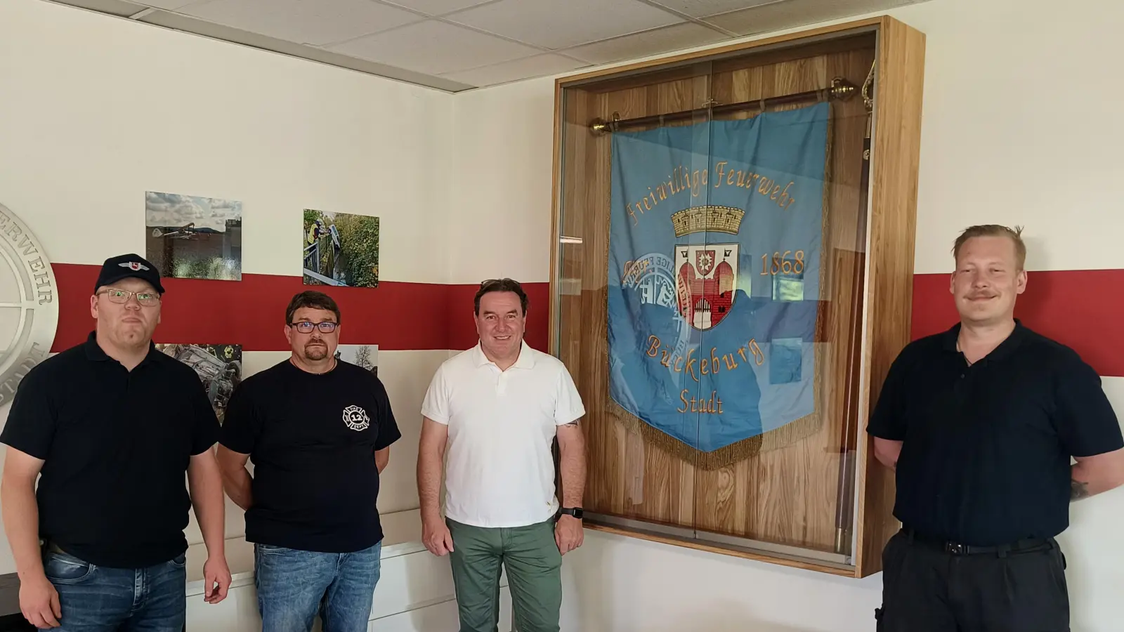 Moritz Gumin, Heiko Reinke, Thorsten Bolte und Ortsbrandmeister Andy Bautze vor der neuen Eichen-Vitrine, den Bildern und dem Edelstahlschild. (Foto: privat)