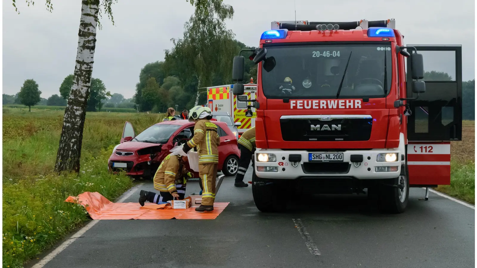 Feuerwehrleute räumen Geräte wieder ins Einsatzfahrzeug, dahinter links das verunglückte Fahrzeug. <br> (Foto: Feuerwehr)