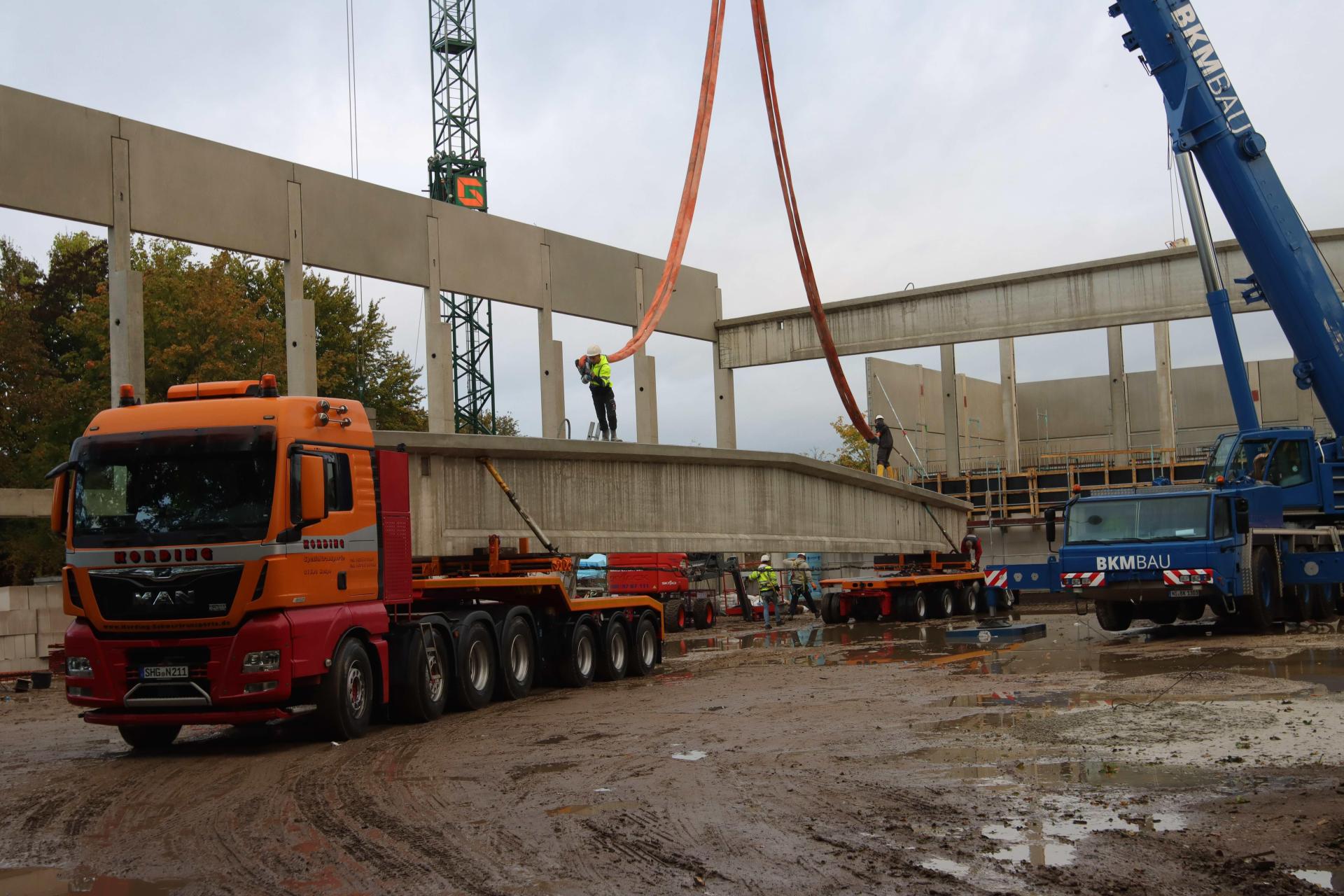 Auf der Baustelle: Mitarbeiter befestigen Halteseile eines Spezialkrans an den Dachträgern. (Foto: tau)