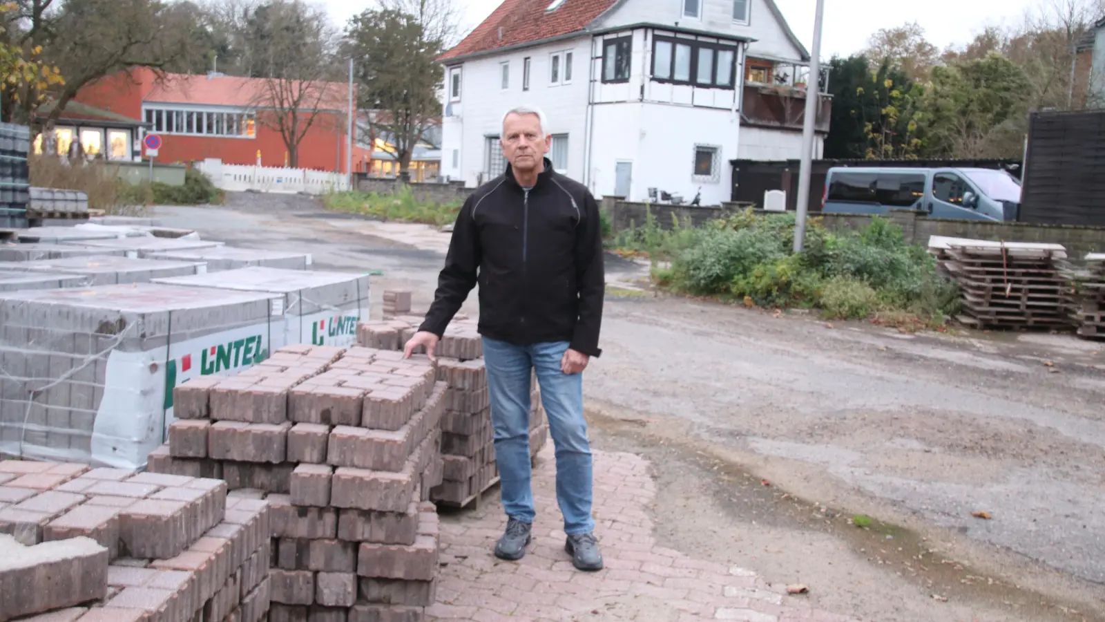 Bernd Heidorn steht an den Steinen, die die Parkflächen versperren: Er hofft, dass Anfang Dezember dort wieder Autos parken können.  (Foto: gi)